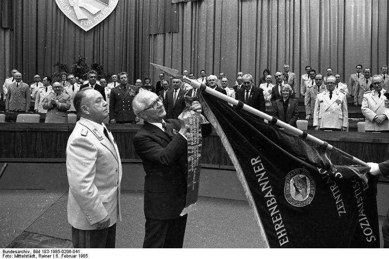 Jahrestag Ministerium für Staatssicherheit.Dieser Fahnenhokuspokus (von: hoc est enim corpus meum beim Abendmahl) soll die Opferlust stärken und das schlechte Gewissen beruhigen.